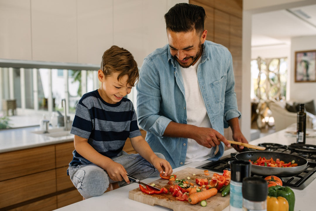 Vater und Sohn schneiden und kochen Gemüse