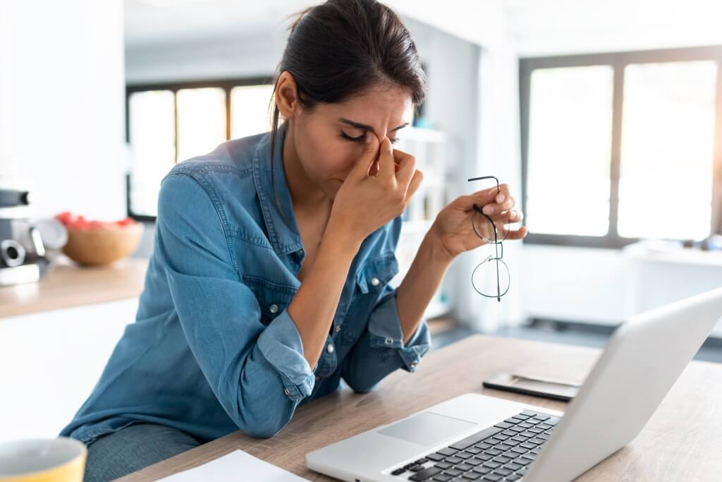 Frau mit Müdigkeit und Kopfweh im Büro: Symptome der Anämie