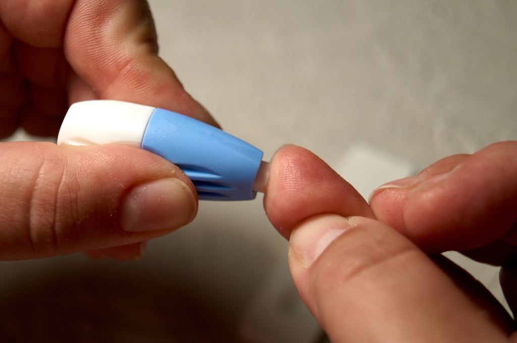 HbA1c-Test für den Langzeitblutzucker: Frau nimmt sich Blutprobe aus der Fiungerspitze