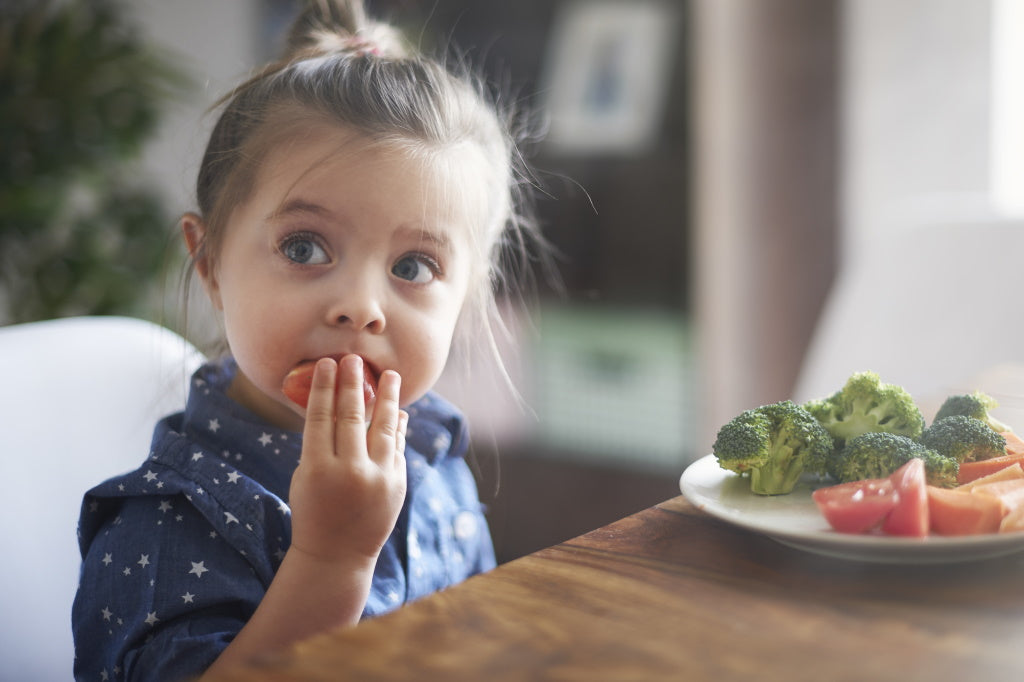 Gesunde Ernährung für Kinder - kleines Mädchen isst Gemüse