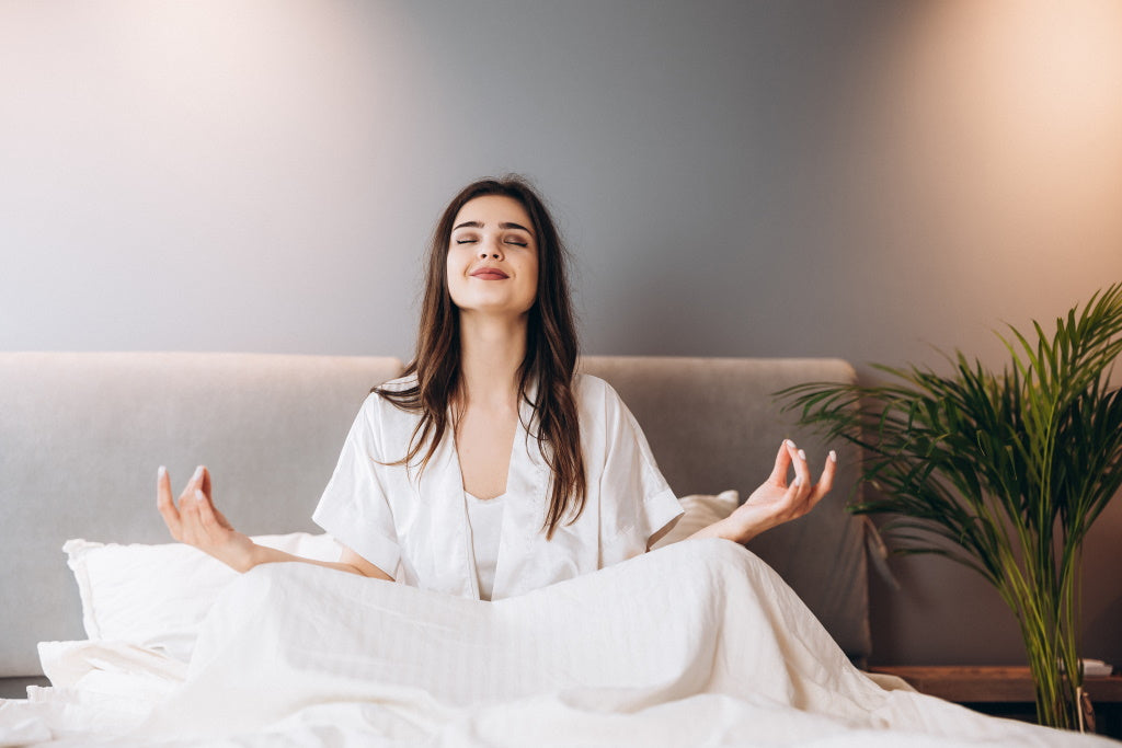 Abendroutine: Junge Frau meditiert im Bett