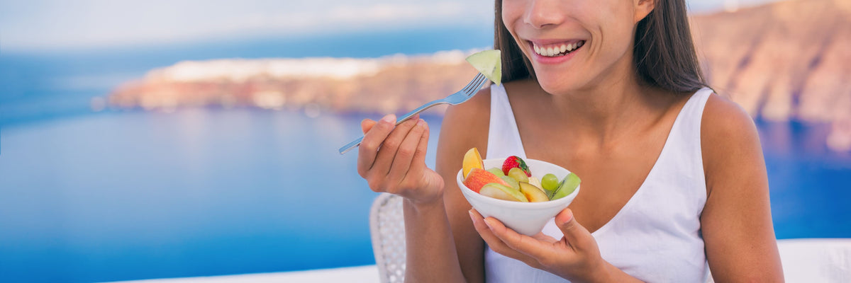 Kalorienarme Snacks - Frau isst Obst im Urlaub
