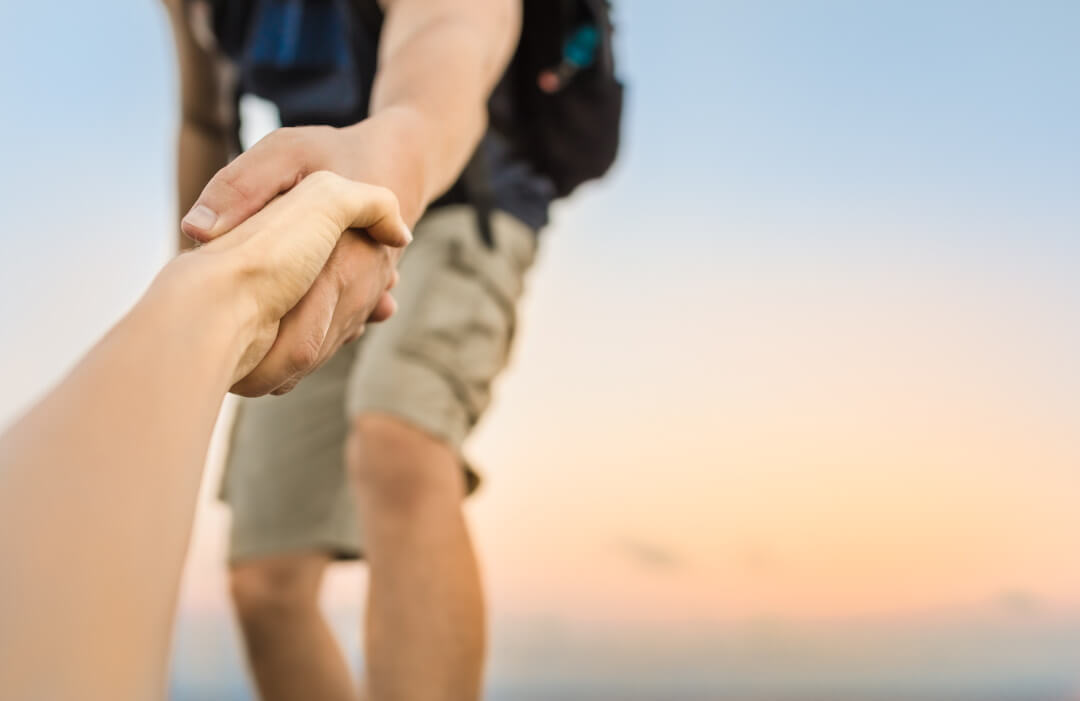 Mann reicht anderem die Hand beim Klettern