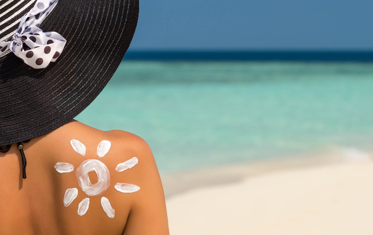 Sonnenbrand - Frau mit Sonnencreme und Hut