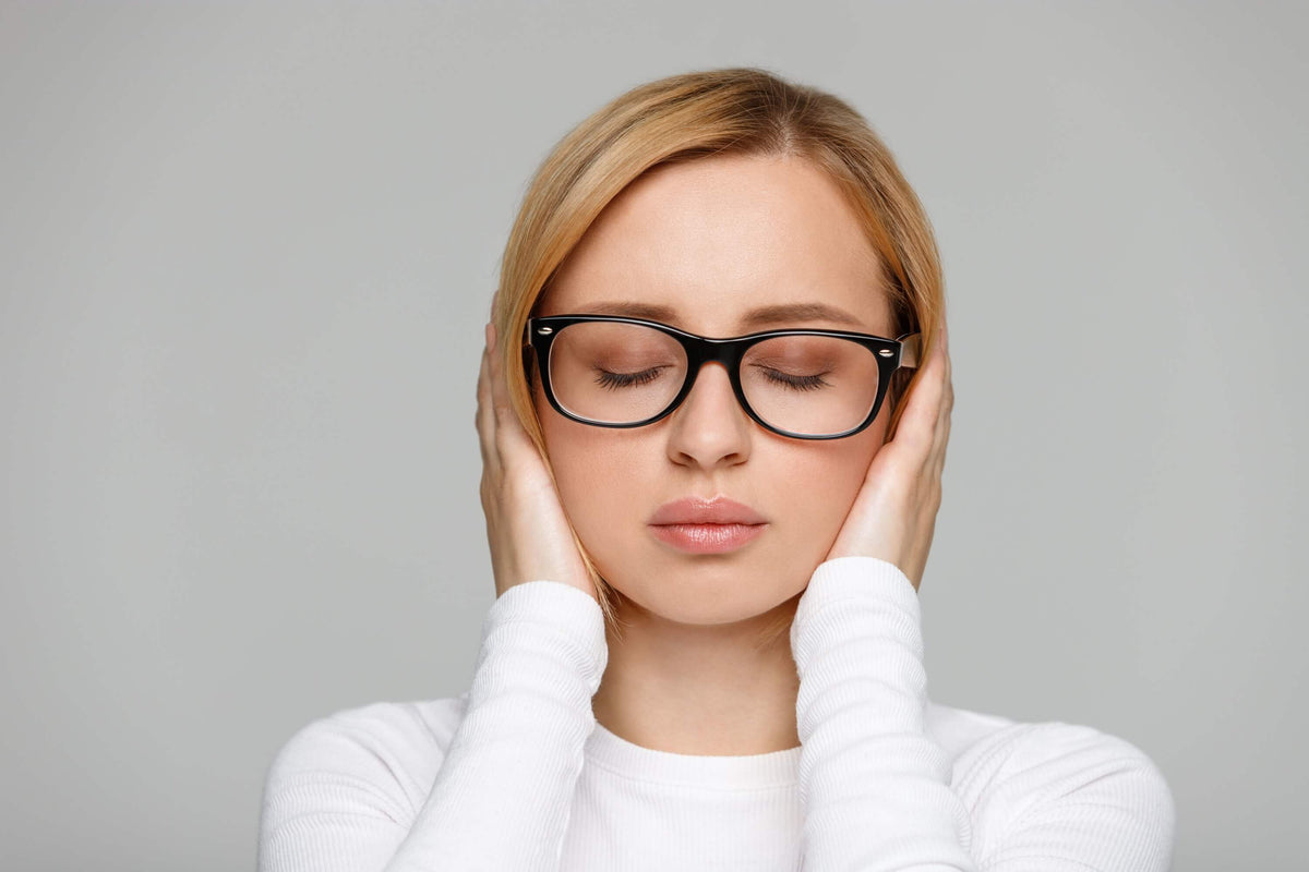 Frau hält sich die Ohren - Tinnitus