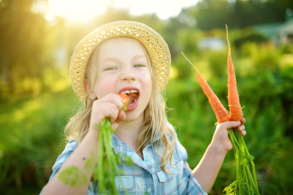 Vitamin A - Mädchen beißt in frische Karotte